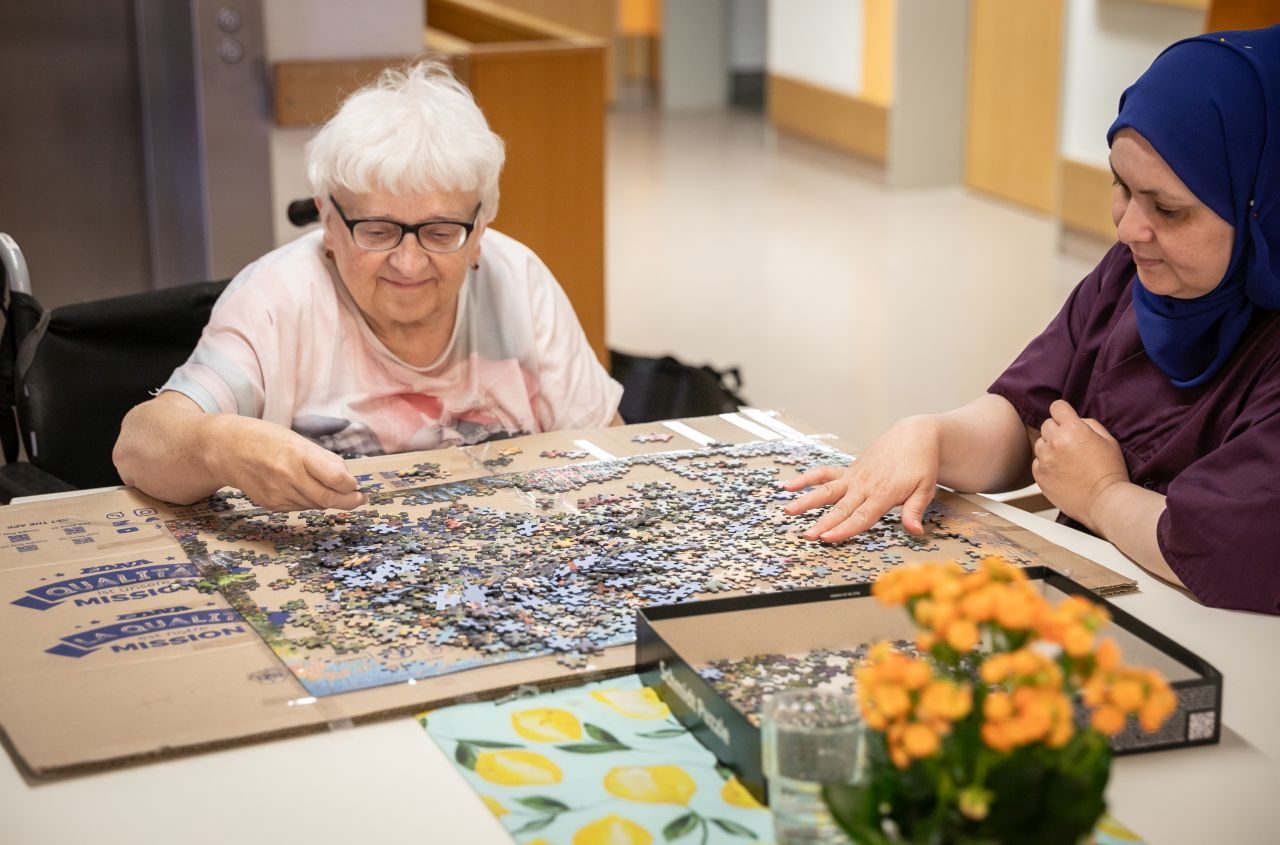 Bewohnerinnen und Betreuungskraft beim gemeinsamen Puzzeln
